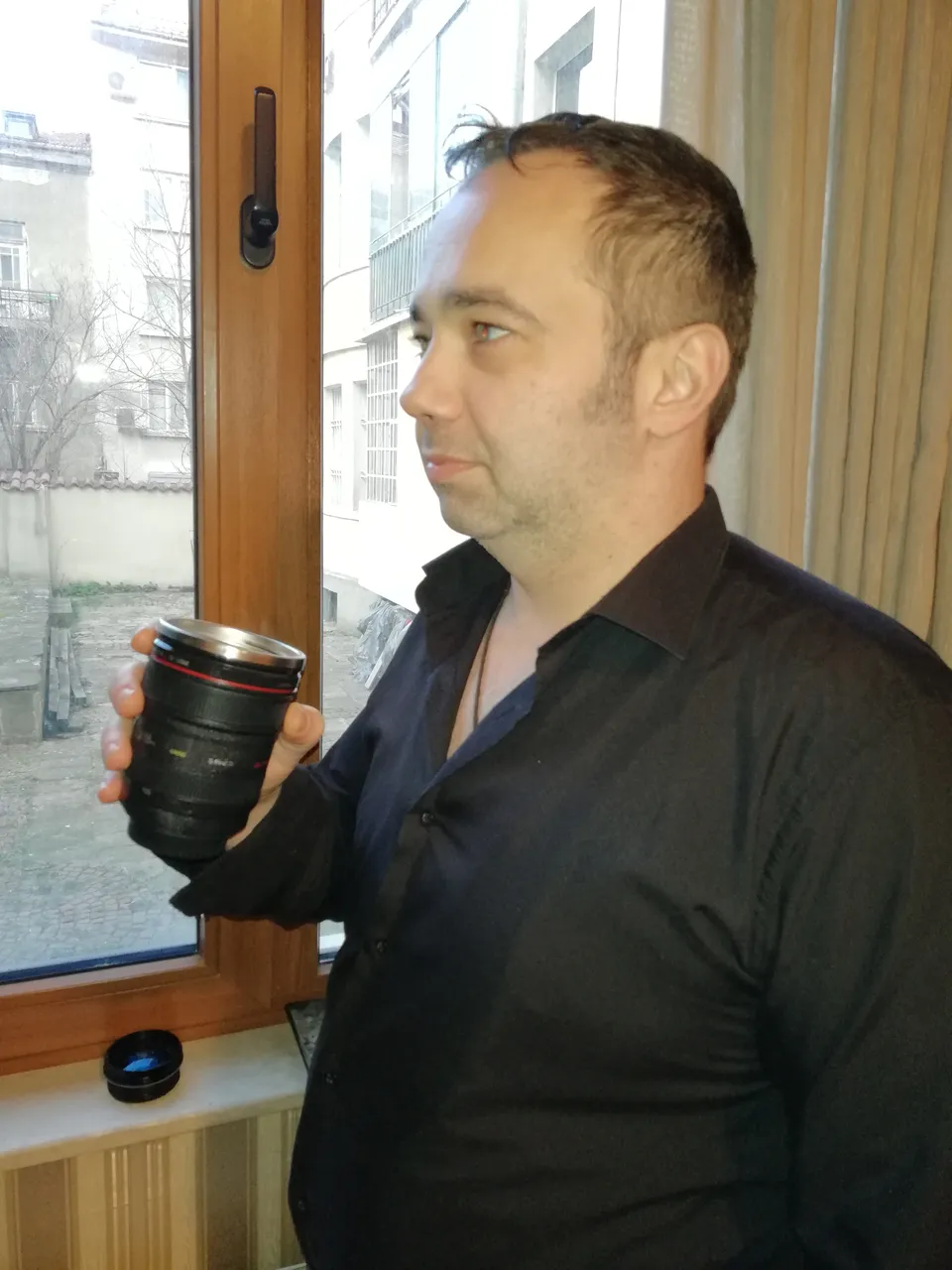 Ivan Pasev holding a cup indoors near a window.